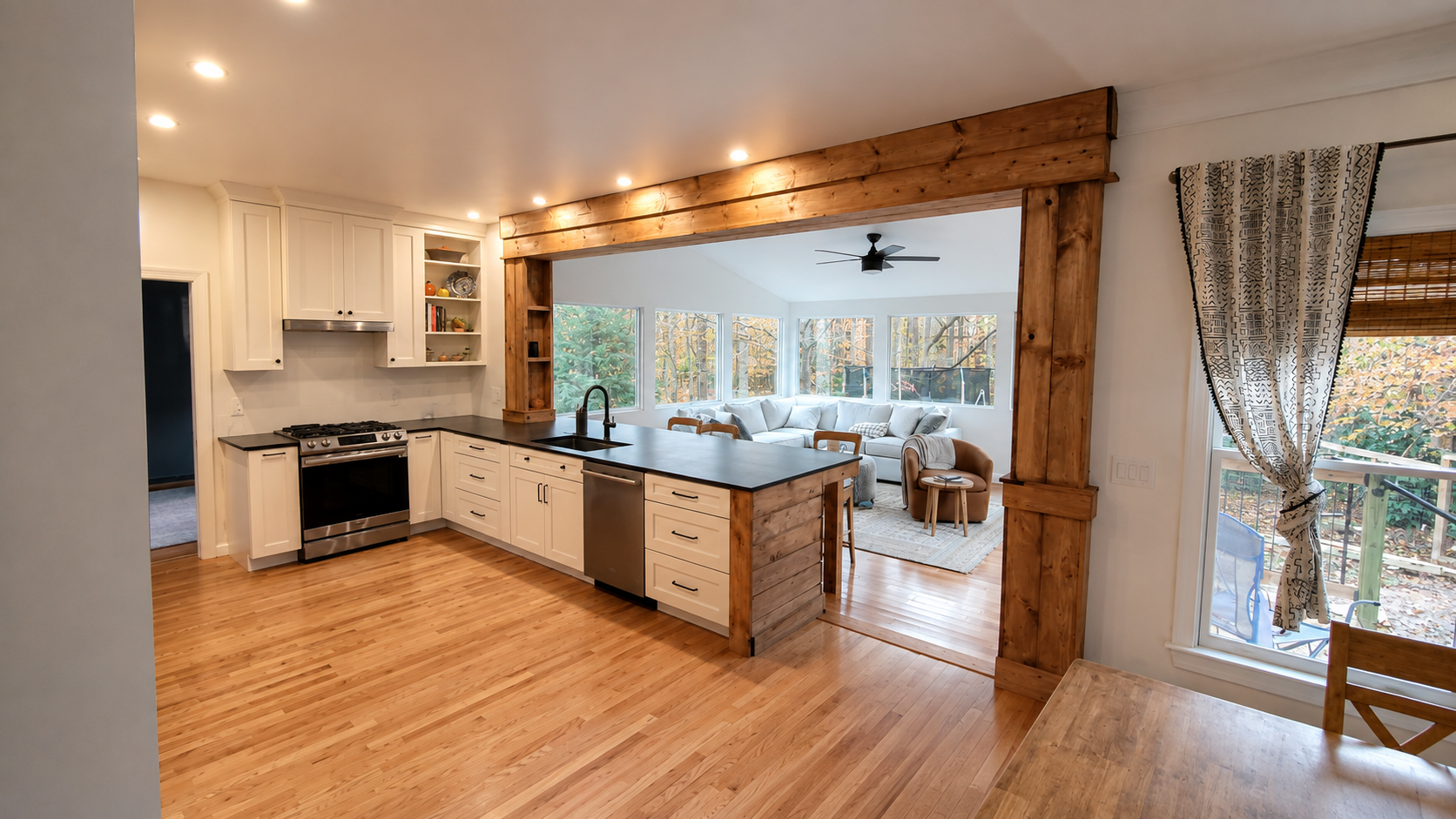 Finished kitchen with white cabinetry, dark counters, and an opening to the furnished sunroom.